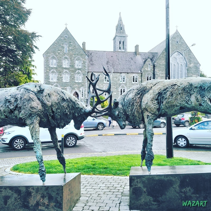 Bâtiment religieux à Killarney, avec au premier plan une sculpture de deux cerfs qui se battent
